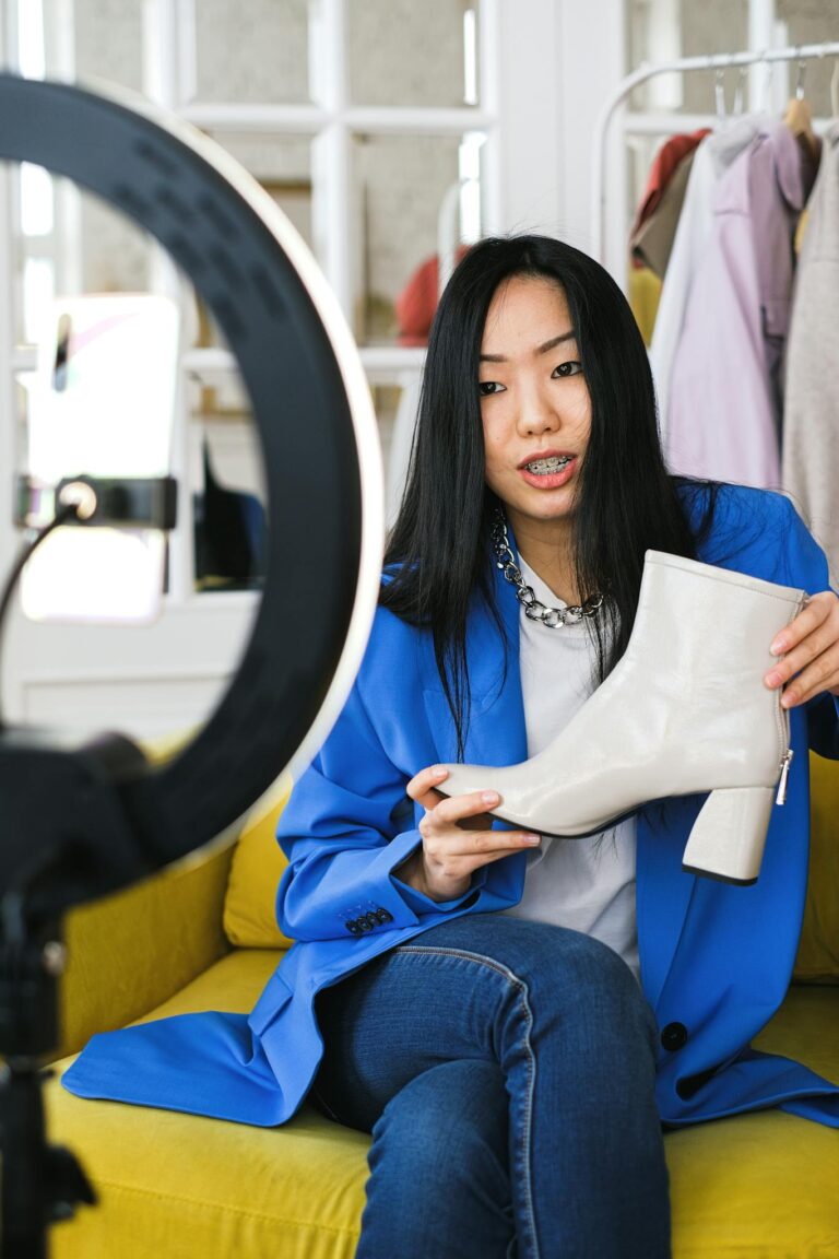 Young woman fashion vlogger recording a video about stylish white boots indoors.