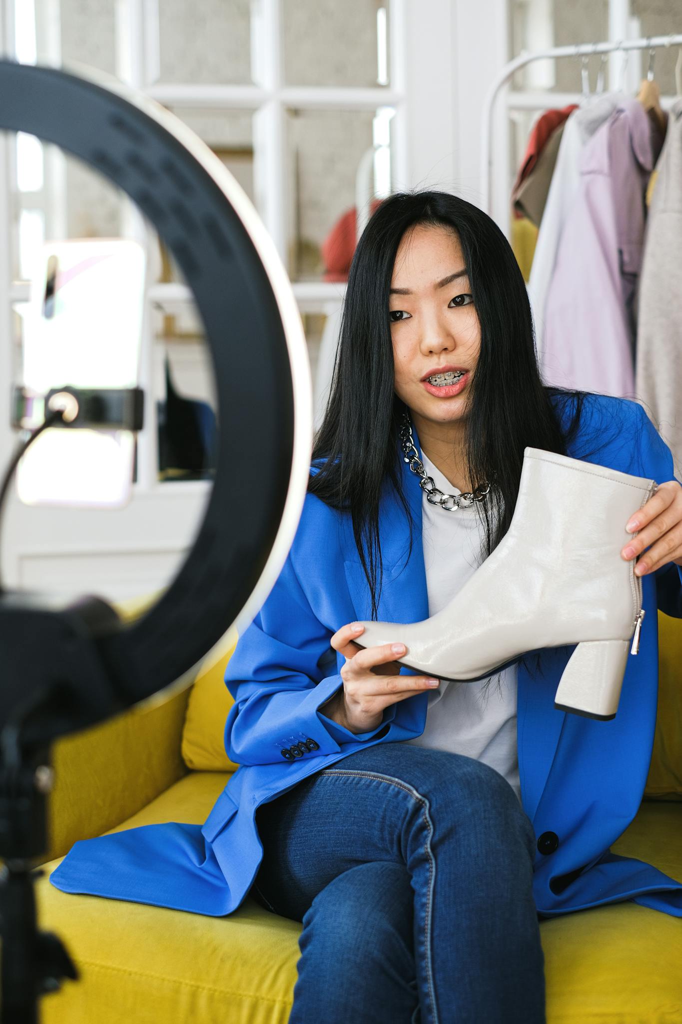 Young woman fashion vlogger recording a video about stylish white boots indoors.